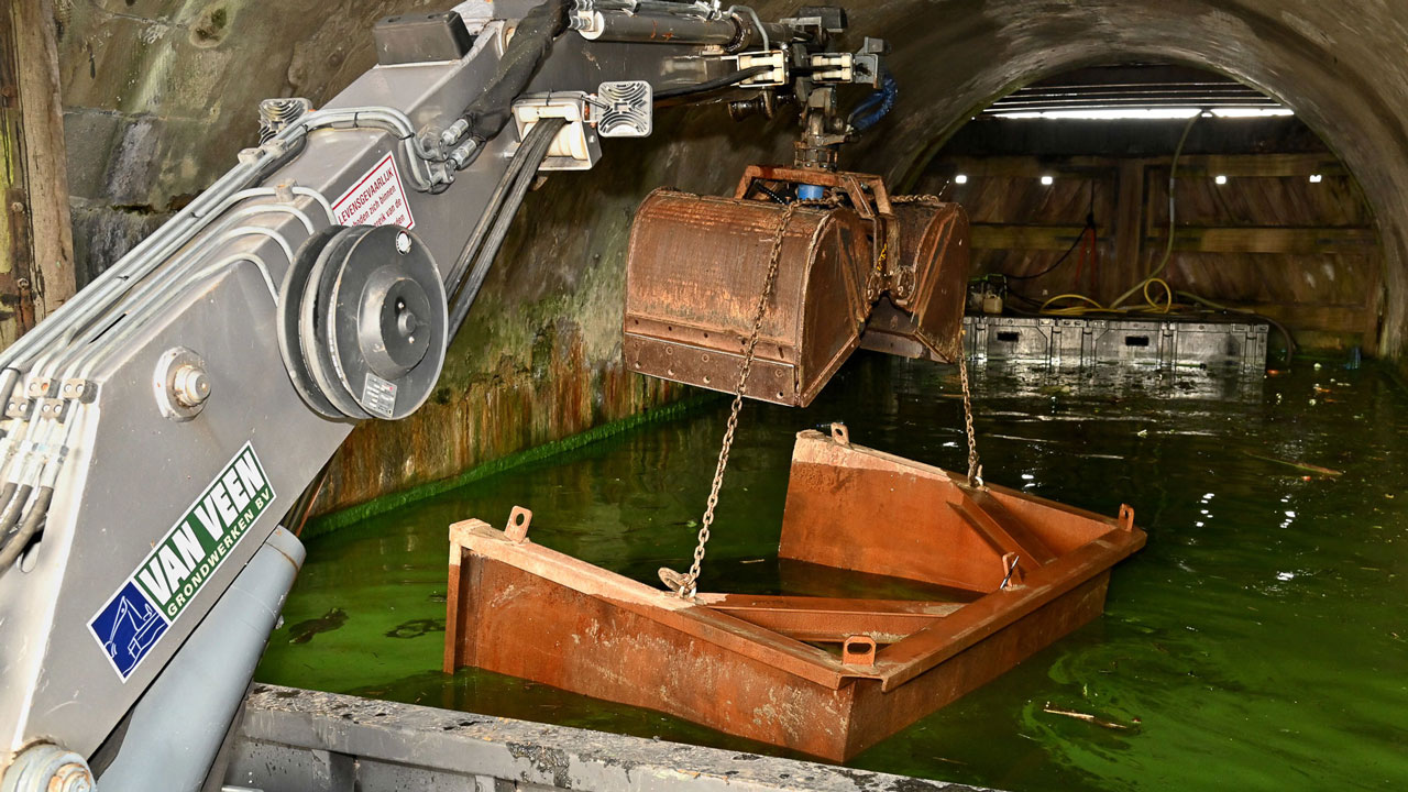 Mechanische arm tilt metalen bak voor baggerwerkzaamheden in Woerdersluis Spaarndam; Tetra Tech brengt staat van historisch kunstwerk uit 1611 in beeld met 3D-techniek