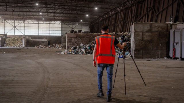 Tetra Tech-milieu-inspecteur met statief in industriële loods – toezicht en veiligheid bij milieukundige inspecties in de afvalverwerking