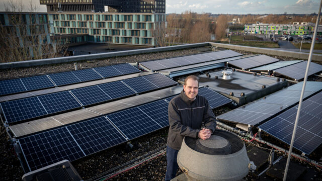 Medewerker op dak met zonnepanelen, illustratie van duurzame gebouwbeheerpraktijken en NEN2580-oppervlaktebepaling in de gebouwde omgeving
