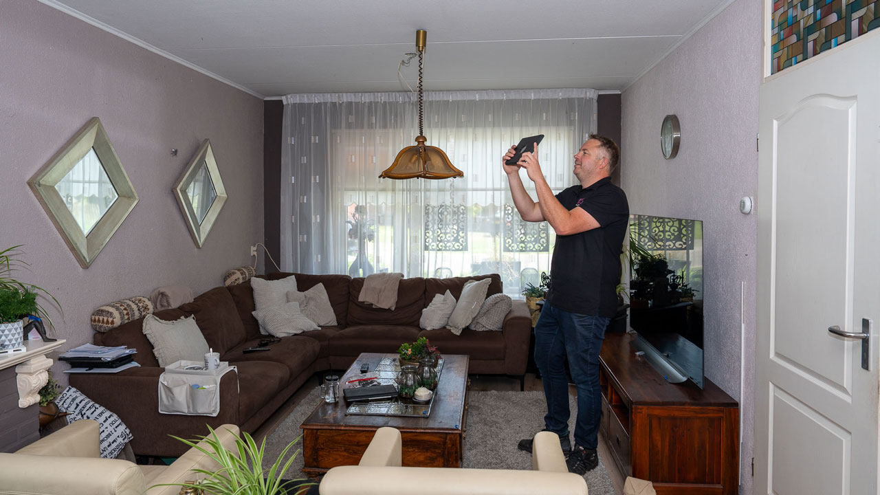 Inspecteur controleert rookmelder tijdens gecombineerde vastgoedinspectie in woonkamer van woning in Emmen of Groningen