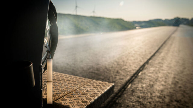 Vers aangelegd asfalt wat nog rookt, gezien van de achterkant van een asfalteermachine