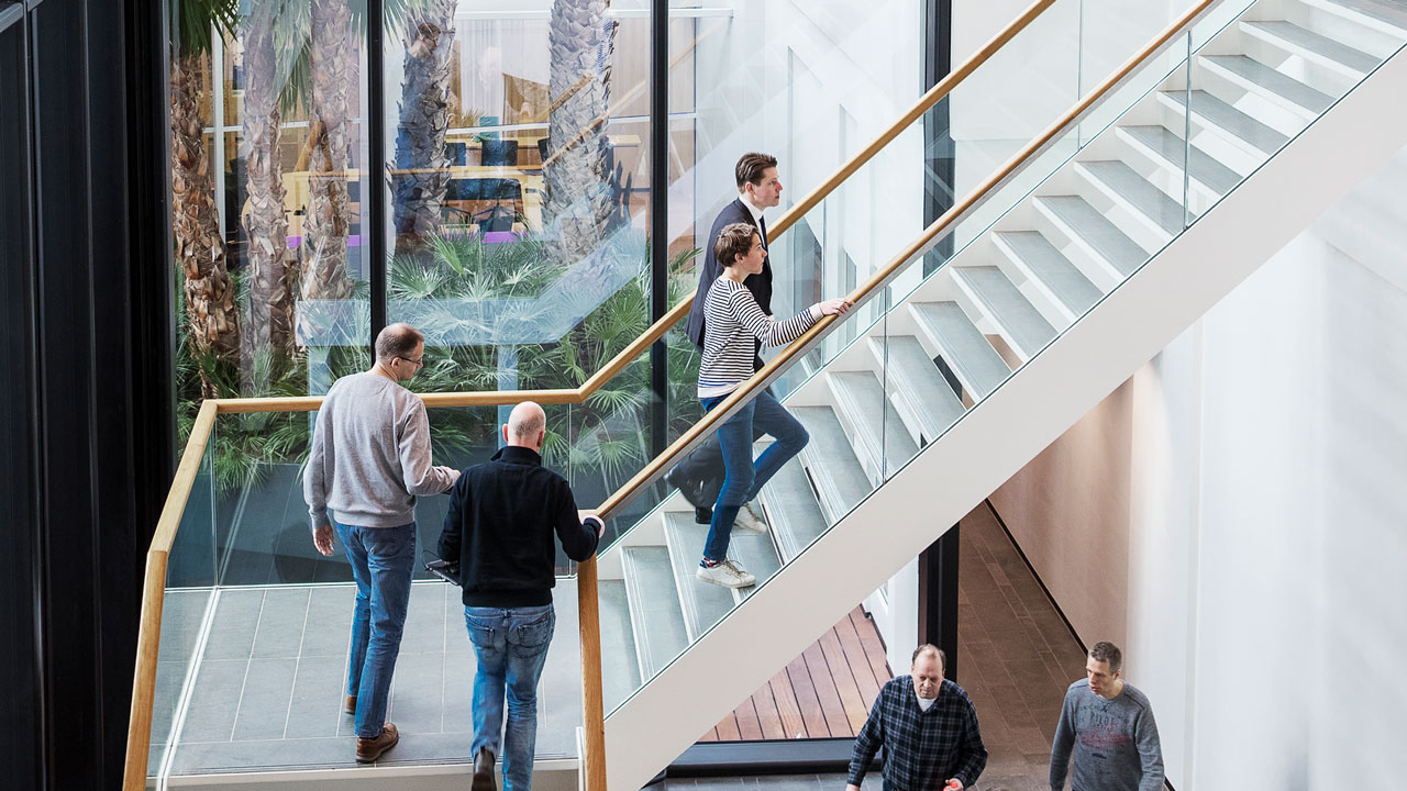 Modern kantoorpand met grote glazen gevel en trap. Mensen lopen de trap op