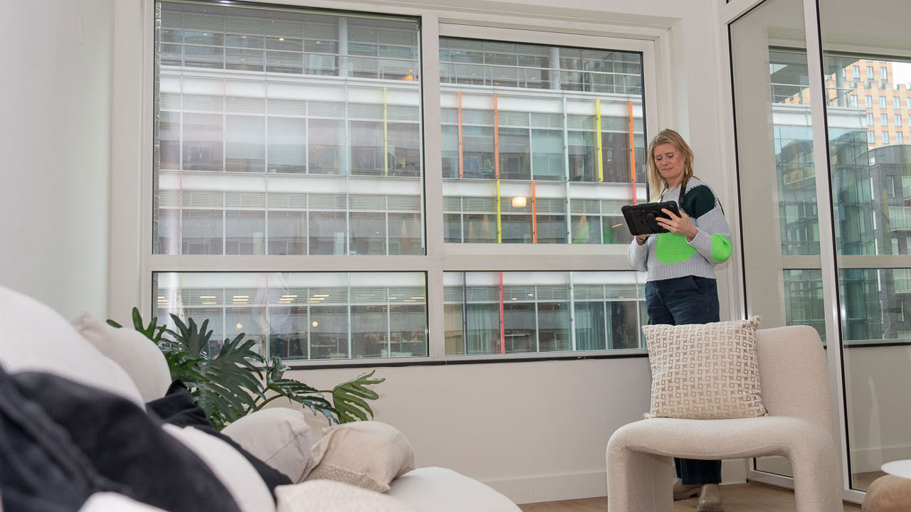 Karla van Stekelenburg met tablet in moderne woonkamer, tijdens het inmeetproject voor Vesteda