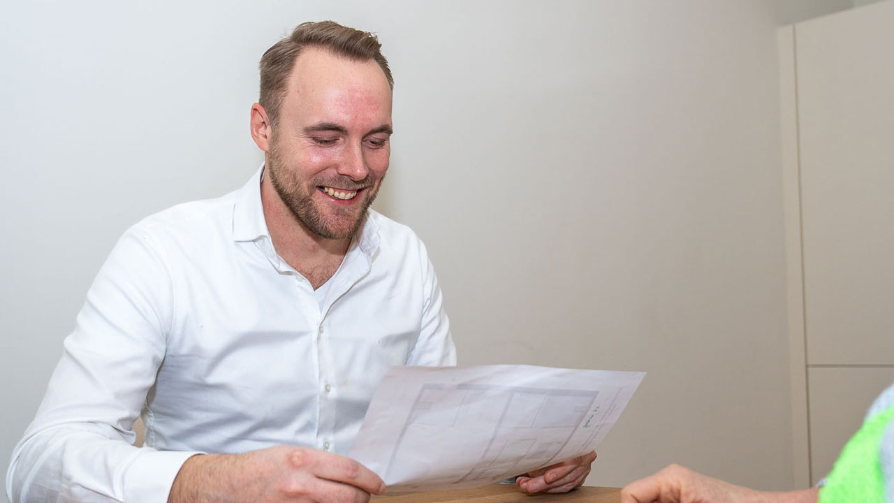 Twee mensen in gesprek aan tafel met papieren en tablet, tijdens het coördineren van het inmeetproject voor Vesteda