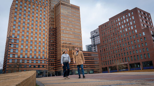 Projectleider Karla van Stekelenburg samen met opdrachtgever Robert van Vesteda op een plein tussen gebouwen