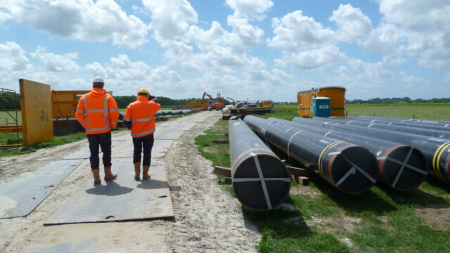 Twee medewerkers op bouwplaats met leidingen en materieel, voor werk aan veilige ondergrondse infrastructuur