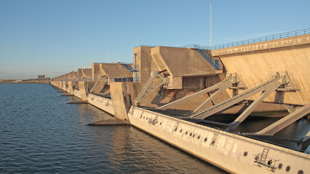 Grote waterbouwkundige constructie met betonnen secties en metalen steunen in het water, ontworpen voor waterbeheersing en veiligheid