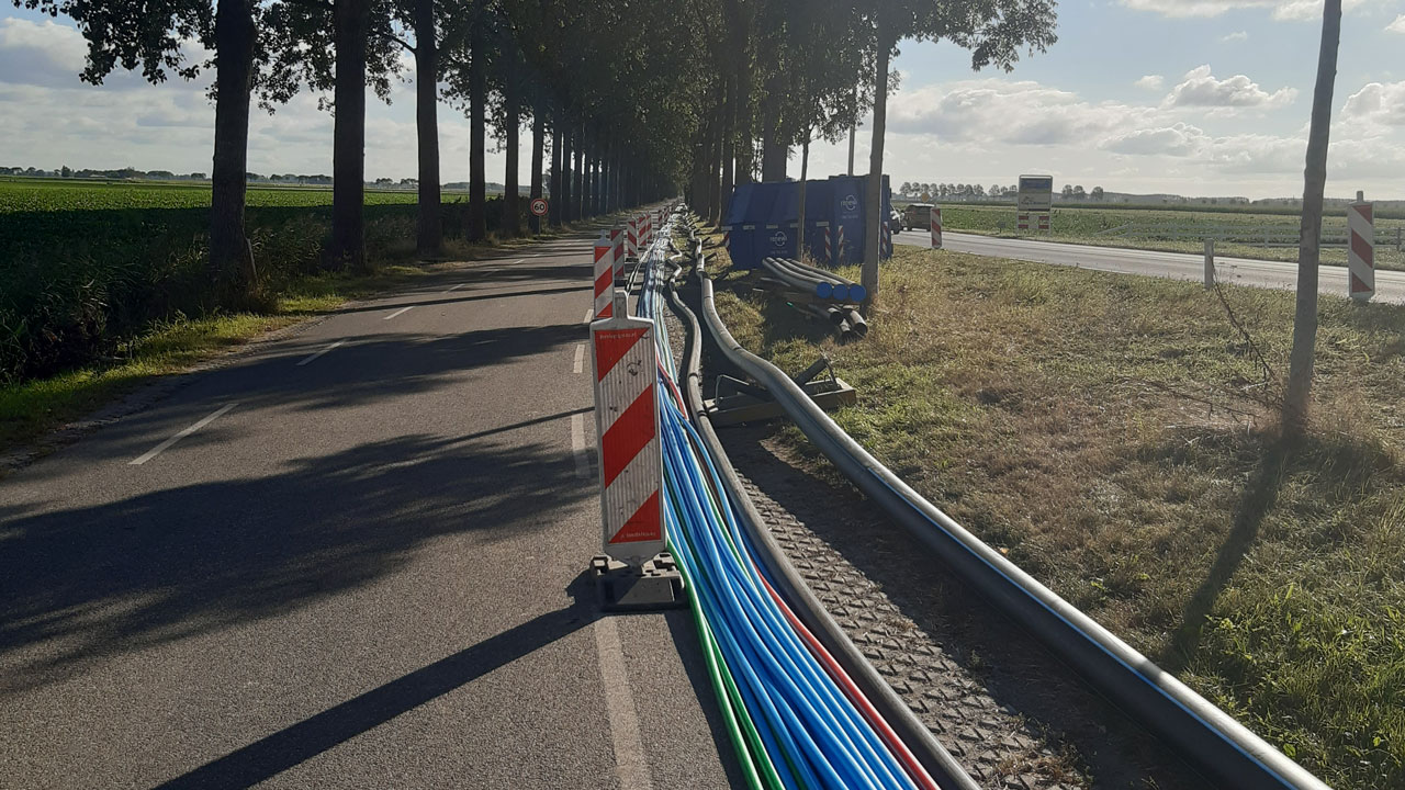 Gekleurde leidingen langs weg met afzetting, aanleg en verlegging van ondergrondse infrastructuur