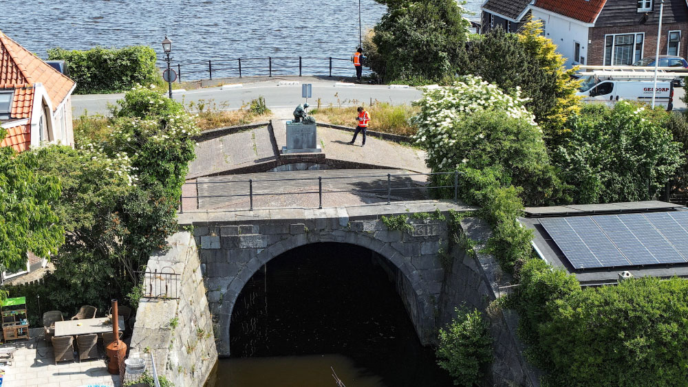 Luchtfoto van brug met Tetra Tech-medewerker in veiligheidsvest boven kanaal – inzet van ROV-onderwaterdrones voor inspectie van civiele kunstwerken in stedelijke omgeving