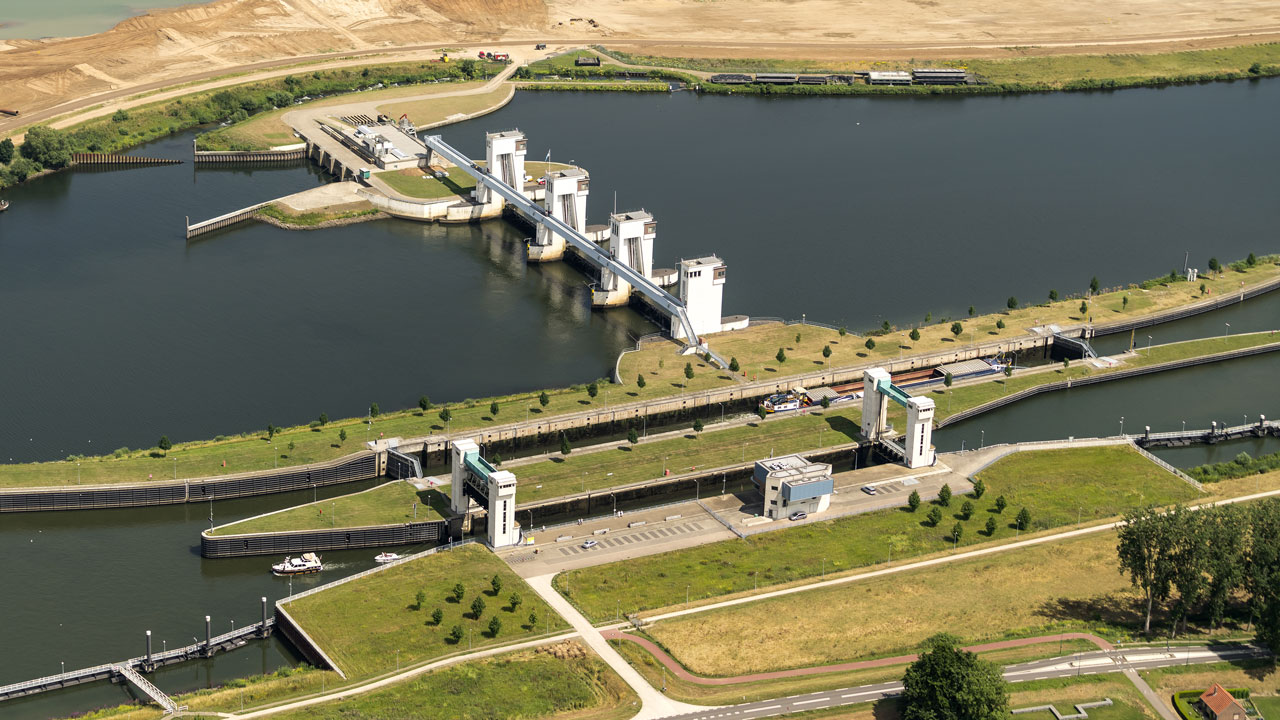 Luchtfoto van waterbouwkundig kunstwerk met sluizen en bedieningsgebouwen, essentieel voor waterbeheer en infrastructuur