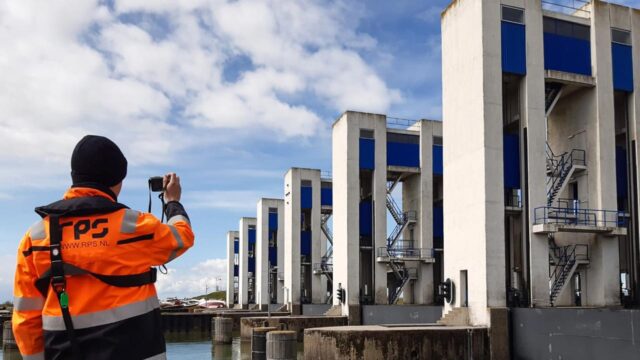 Tetra Tech-medewerker legt betonnen waterbouwkundige constructies vast met blauwe panelen en metalen trappen voor materiaalonderzoek