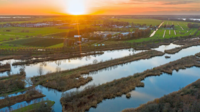 Luchtfoto van Nederlands landschap bij zonsondergang met waterlopen, groenstroken en bebouwing – ruimtelijke analyse en ecologische toetsing in het kader van