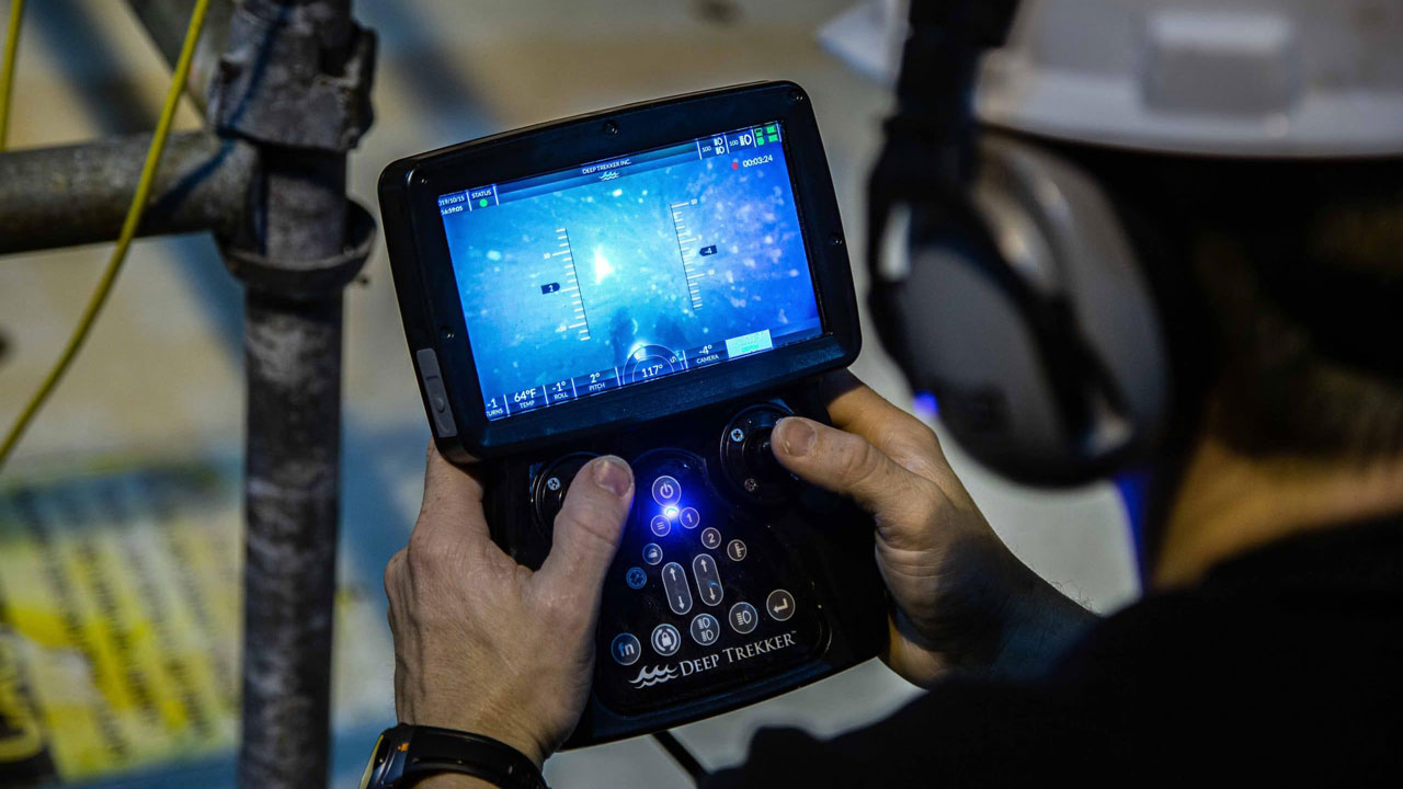 Operator bestuurt Deep Trekker ROV met handheld controller en scherm met onderwaterbeeld