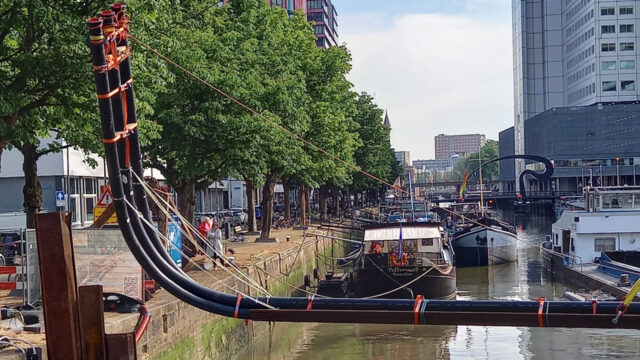 Kanaal met aangelegde leidingen boven water in stedelijke omgeving, onderdeel van tracé-engineering en infrastructuurontwikkeling