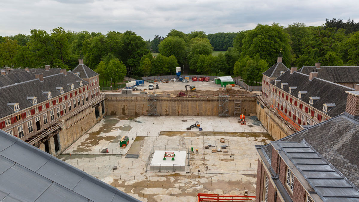 Bouwplaats Paleis Het Loo tijdens asbestsanering, historische omgeving met excavatie en materieel in groene, bosrijke setting