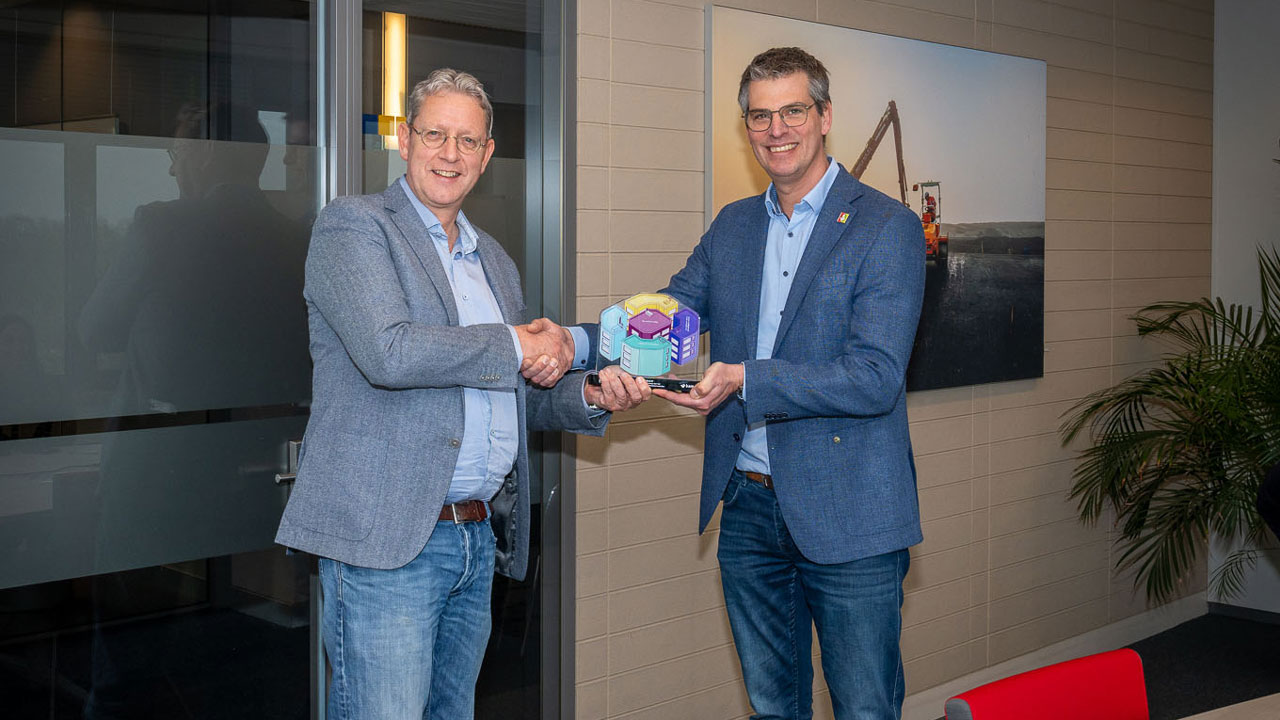 Twee personen schudden handen bij overhandiging award in kantoor, illustratie van erkenning voor veiligheid in de bouwsector