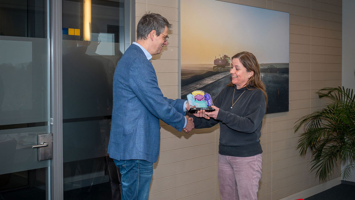 Overhandiging van award met handdruk in kantoorruimte, illustratie van erkenning voor veiligheidsprestaties in de bouwsector