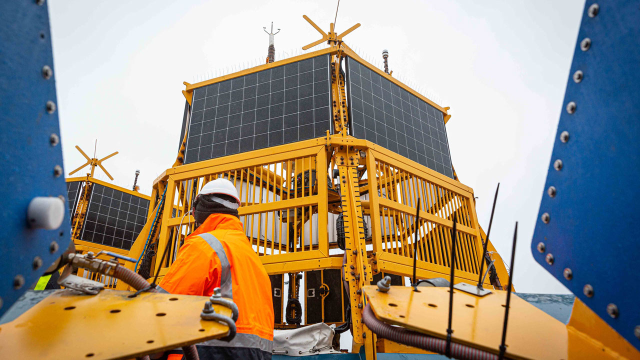 Medewerker bij LiDAR-boei met zonnepanelen, essentieel voor metingen van wind, stroming en getijden op de Noordzee
