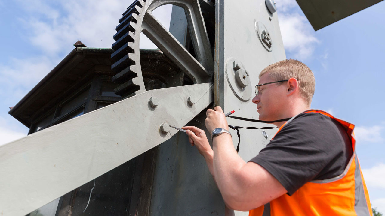 Medewerker in oranje veiligheidsvest neemt monster van brugonderdeel voor chroom 6 einbeoordeling
