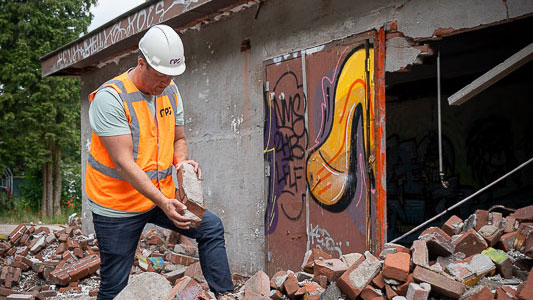 Medewerker met helm en baksteen tussen puin – circulair slopen met oog voor hergebruik en duurzame materiaalstromen
