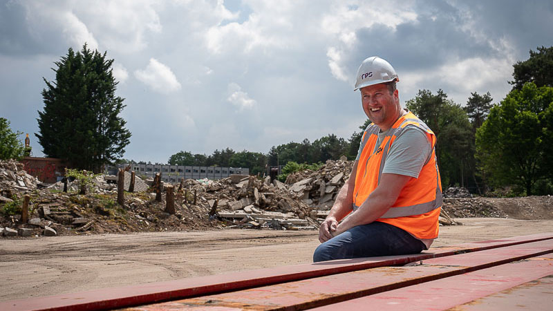 Medewerker op stapel rode stalen profielen – focus op hergebruik van staal bij circulair slopen en duurzame bouw