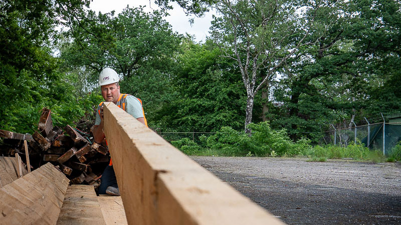 Medewerker werkt met houten balken op buitenterrein – hergebruik van hout als onderdeel van circulair slopen in Nederland