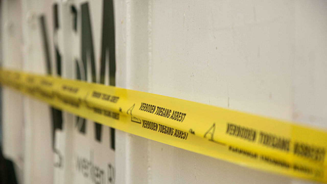 Waarschuwingslint met tekst 'Verboden toegang asbest' bij circulaire sloop van oud schoolgebouw Sterrenwerk in Teylingen