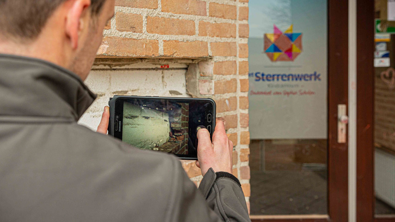 Persoon fotografeert gevel van oud schoolgebouw Sterrenwerk, circulair gesloopt in opdracht van Gemeente Teylingen