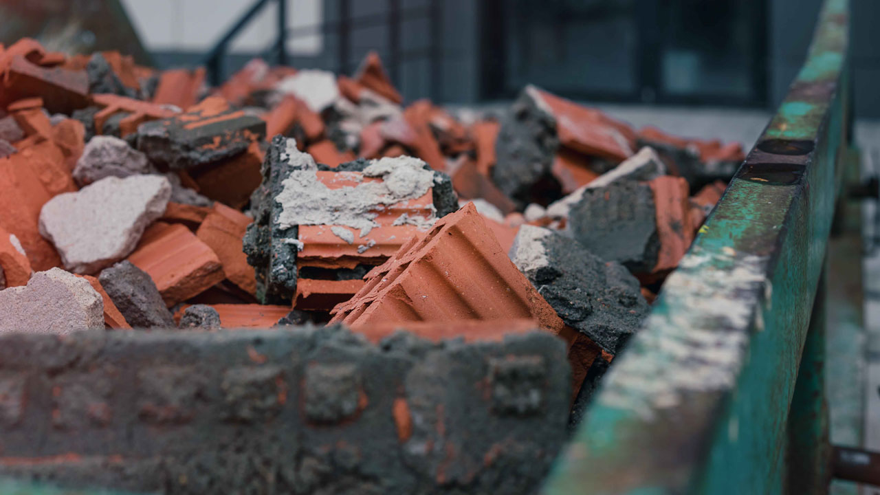 Container met puin van rode bakstenen en beton bij circulaire sloop van schoolgebouw Sterrenwerk in Teylingen