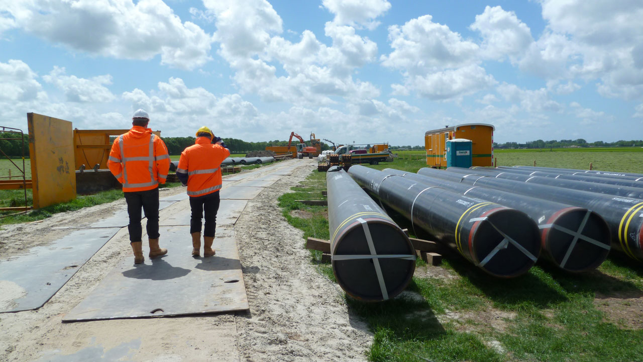 Medewerkers op bouwplaats met leidingwerk: inzet voor veilige aanleg van energie-infrastructuur in de energietransitie
