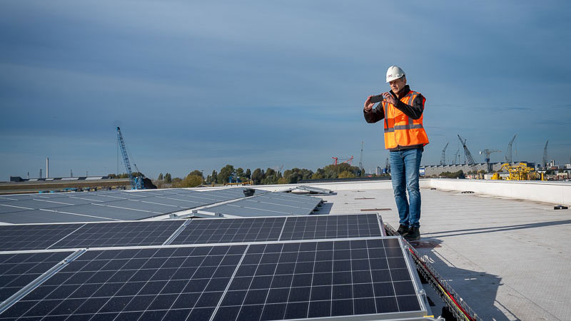 Inspectie van zonnepanelen op dak door medewerker, illustratie van duurzame energieoplossingen bij bouwprojecten in Schiedam