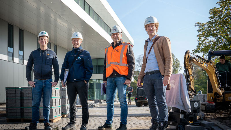 Team op bouwplaats voor modern gebouw met bouwmaterieel, illustratie van samenwerking en uitvoering bij duurzaam bouwen in Schiedam