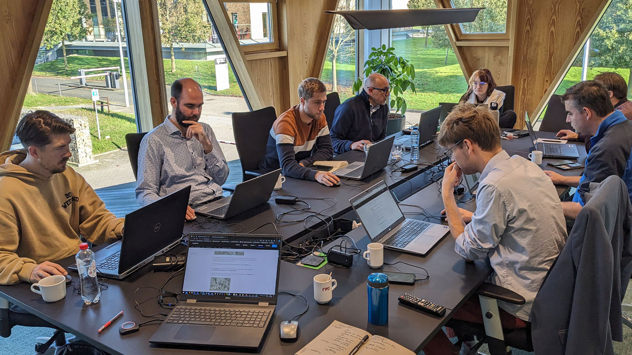 Team werkt met laptops in lichte vergaderruimte, illustratie van samenwerking en digitale workflows met ArcGIS Pro in een moderne kantooromgeving