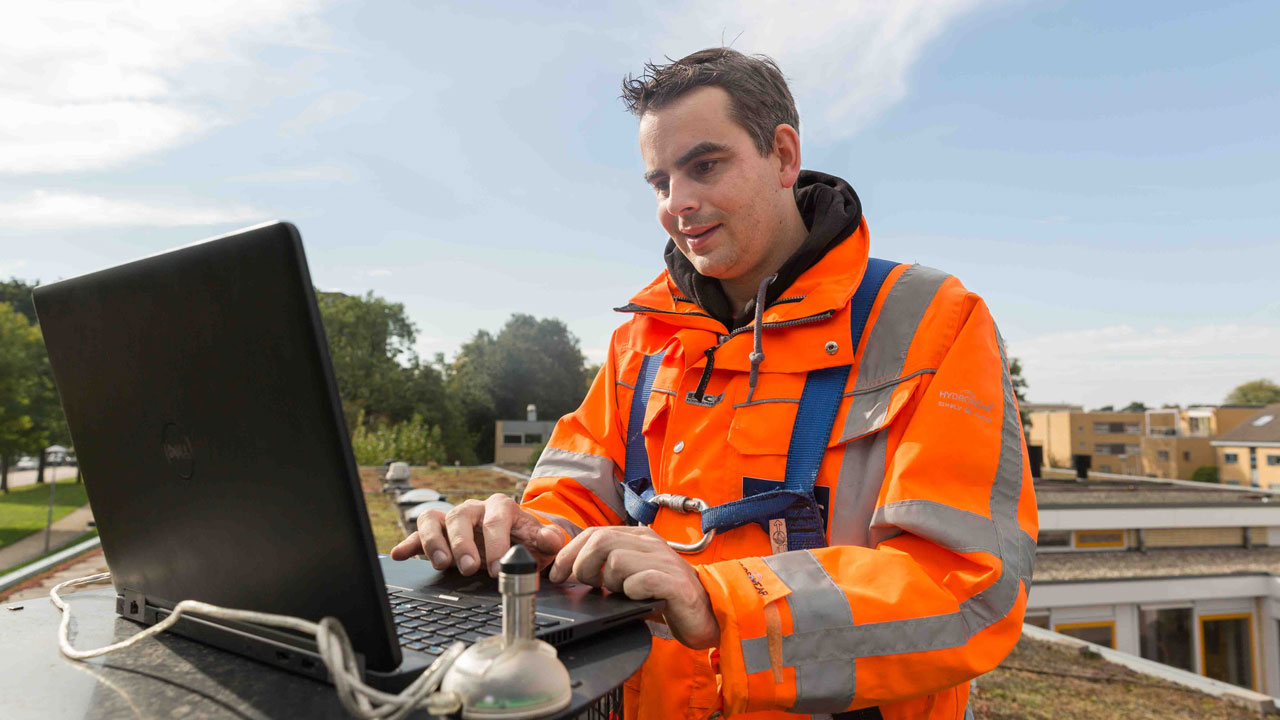 Onderzoeker op groen dak met laptop analyseert effect van vegetatie op daken voor hemelwaterafvoer stedelijk klimaat voor gemeente Utrecht