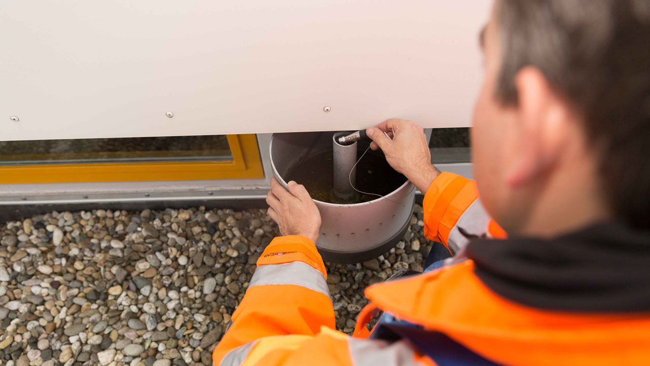 Onderzoeker voert inspectie uit met meetapparatuur in metalen behuizing, onderdeel van monitoring groene daken in stedelijke omgeving