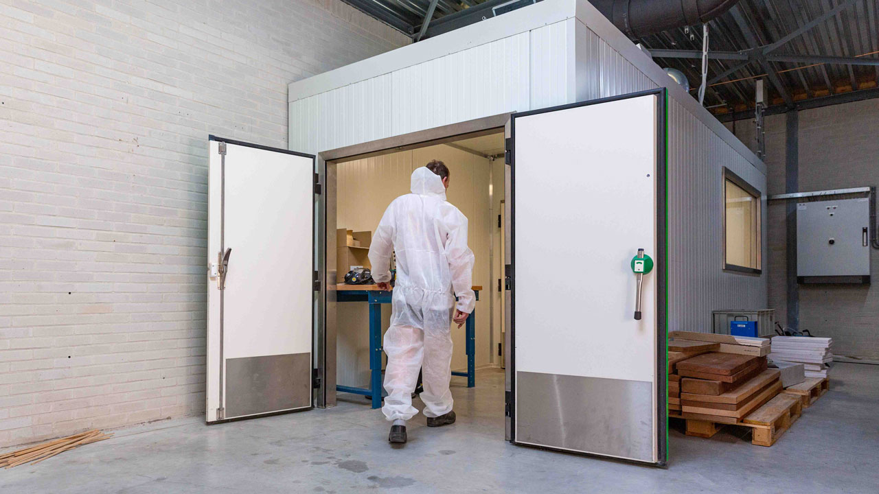 Medewerker in beschermpak betreedt stofvrije ruimte, illustratie van gecontroleerde werkomgeving en veilig werken op de bouwplaats