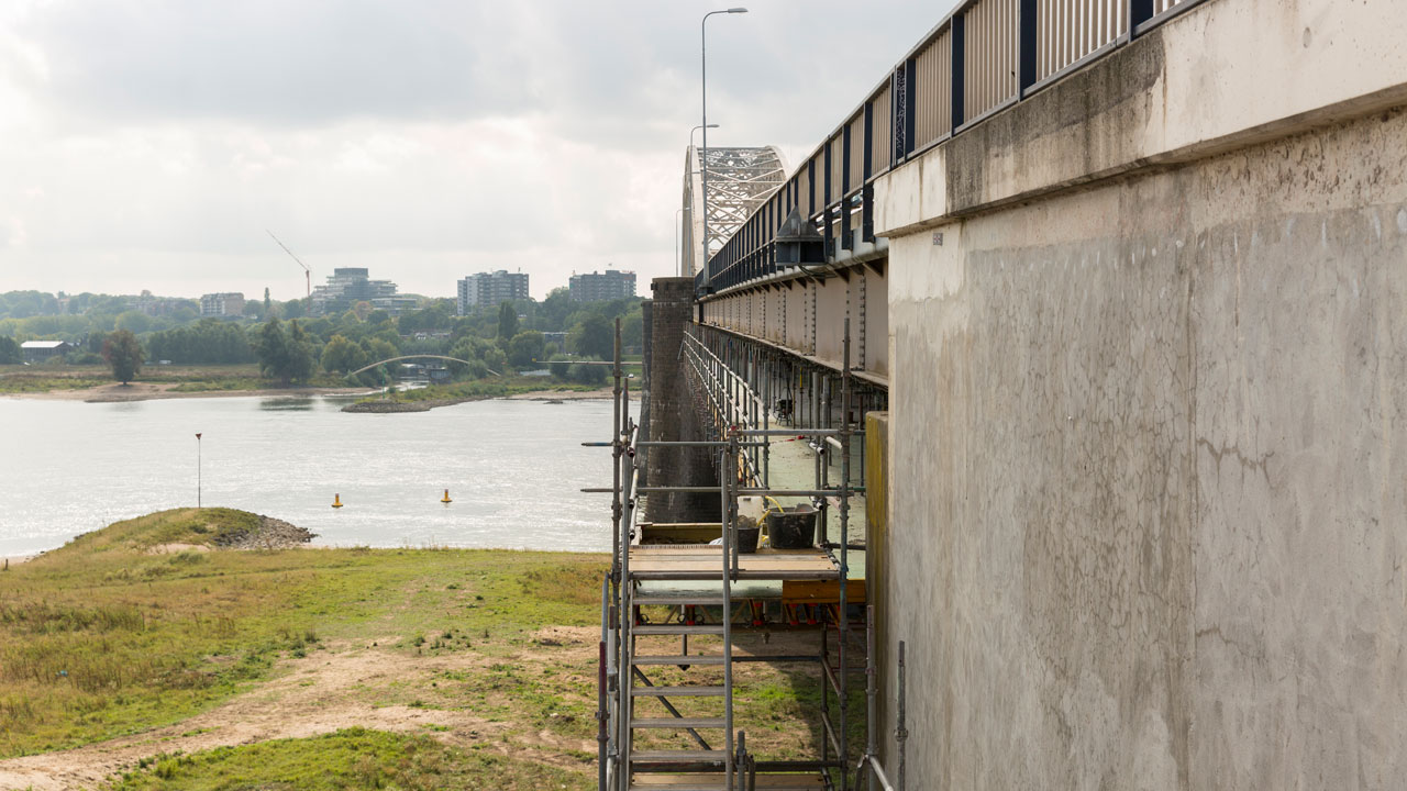 Brug in onderhoud met steigerconstructie voor chroom-6-verwijdering door Tetra Tech, zicht op water en stedelijke achtergrond