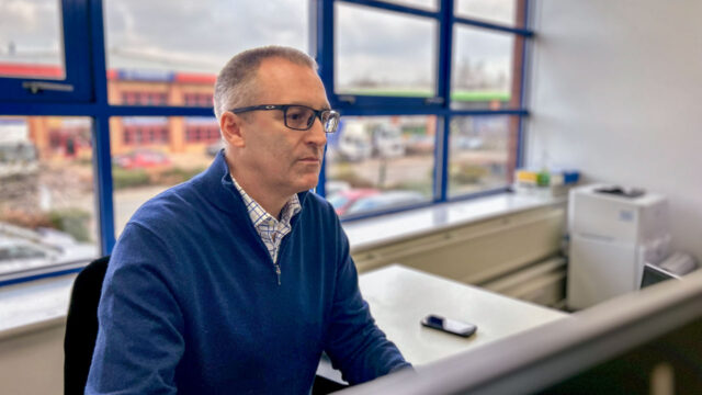 Tetra Tech-expert aan bureau met smartphone – inzet op kennisdeling en onderzoek naar PFAS en de impact op milieu en gezondheid