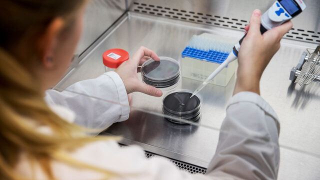 Laboratoriummedewerker plaatst monsterflesje in autosampler voor analyse