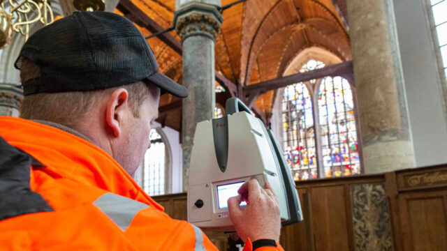 Landmeter met meetapparatuur in de Oude Kerk Amsterdam, bezig met nauwkeurige 3D-opname van het historische interieur