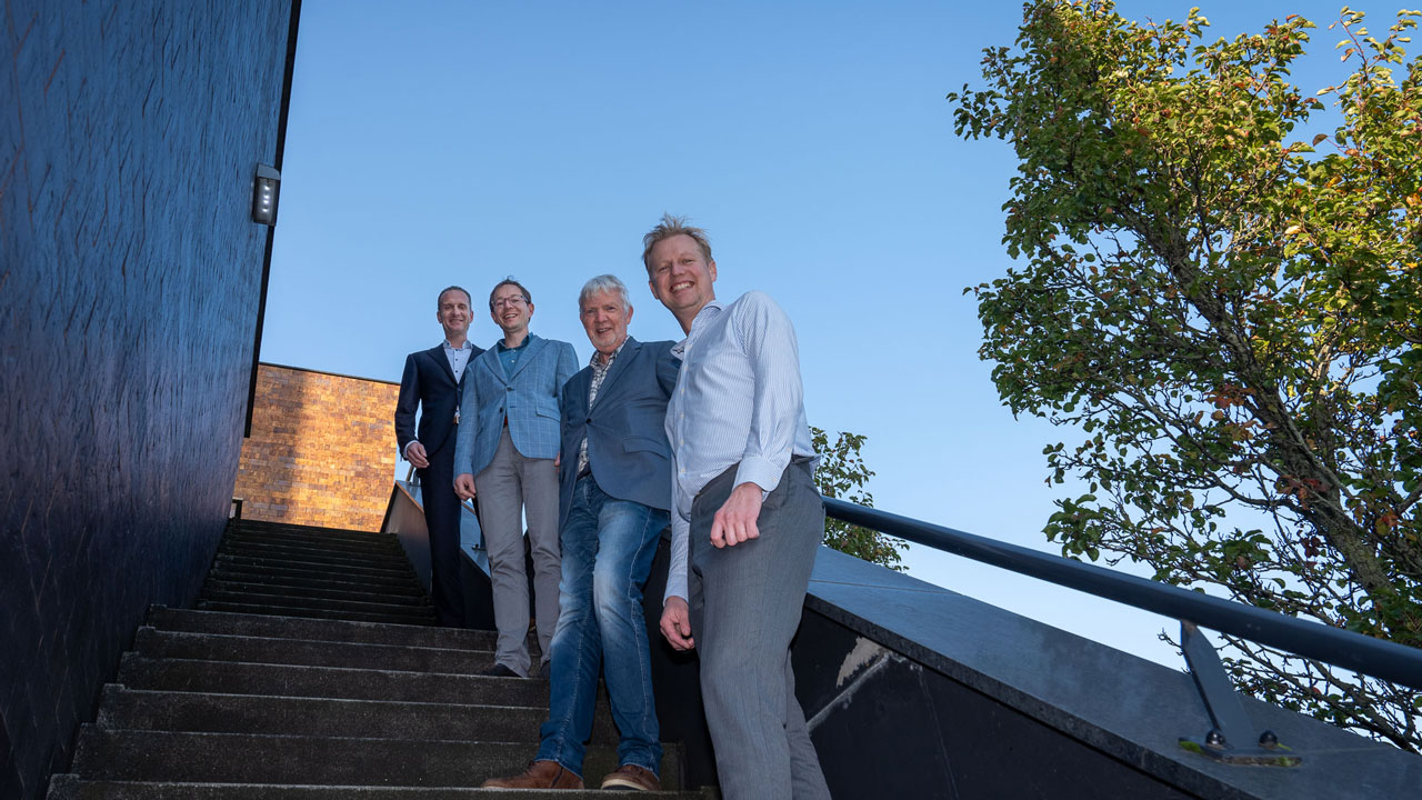 Vier organiserende partners van symposium poseren op buitentrap: samenwerking en kennisdeling centraal tijdens evenement