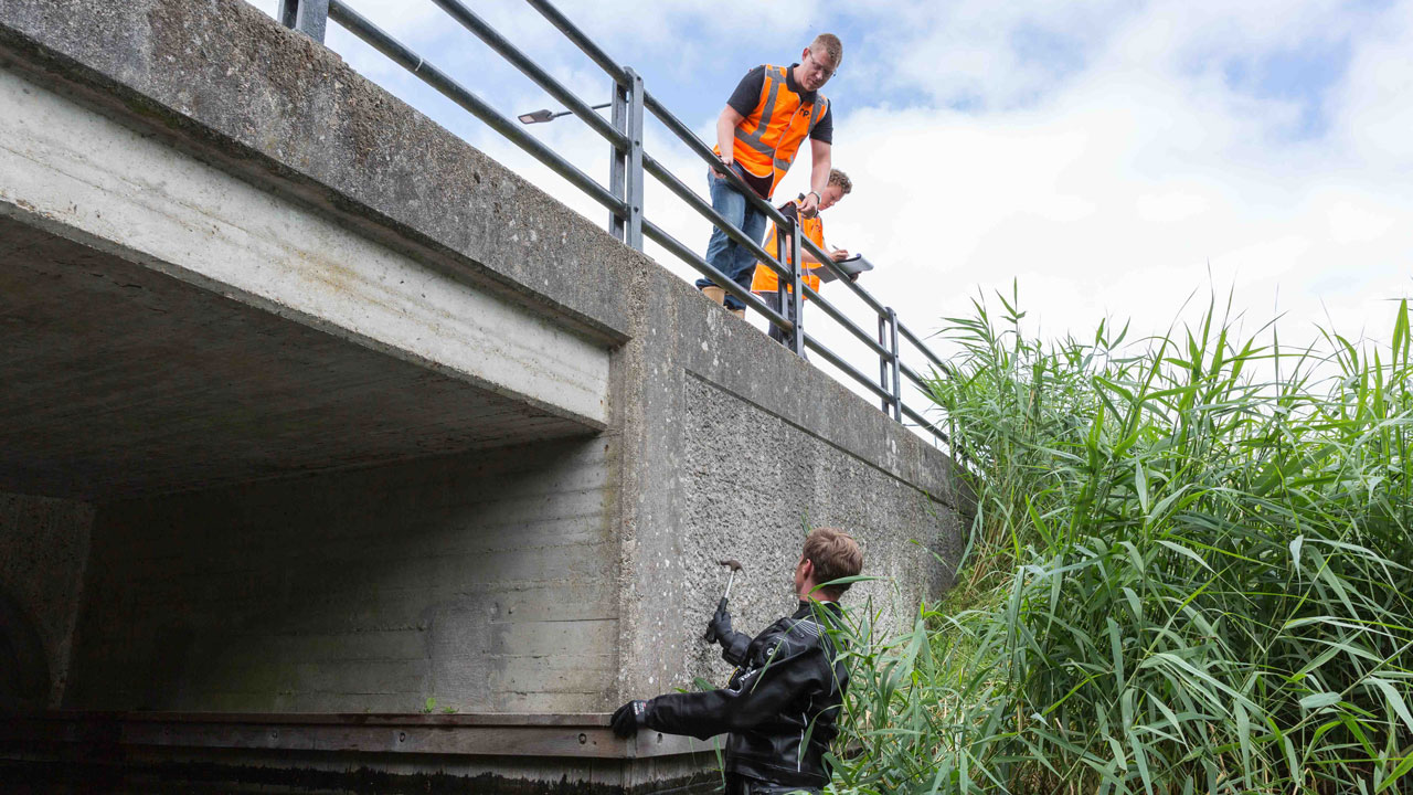 Drie mannen inspecteren stenen brug