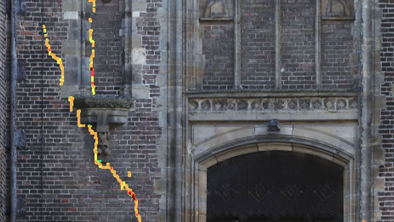 Verticale scheur in bakstenen gevel, gemarkeerd met kleurcodes voor AI-inspectie en analyse van structurele schade