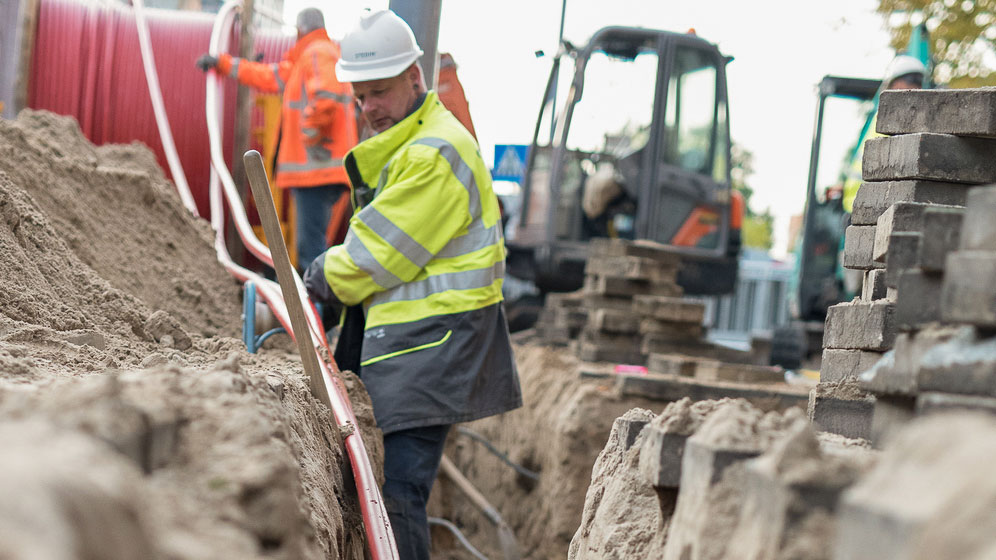 Werkzaamheden aan ondergrondse kabels door monteurs in veiligheidskleding, onderdeel van uitbreiding hoogspanningsnetwerk met Tetra Tech