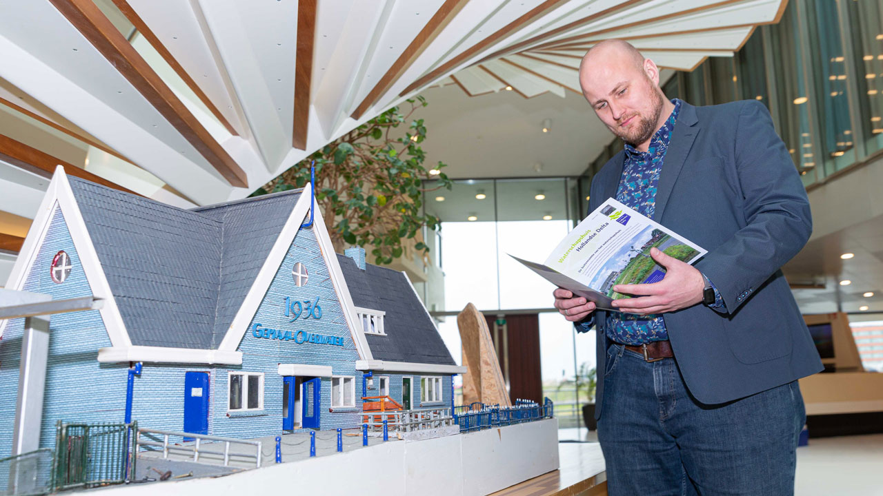 Persoon bekijkt maquette van duurzaam gebouw in moderne ruimte, illustratie van strategische labels in vastgoedbeheer