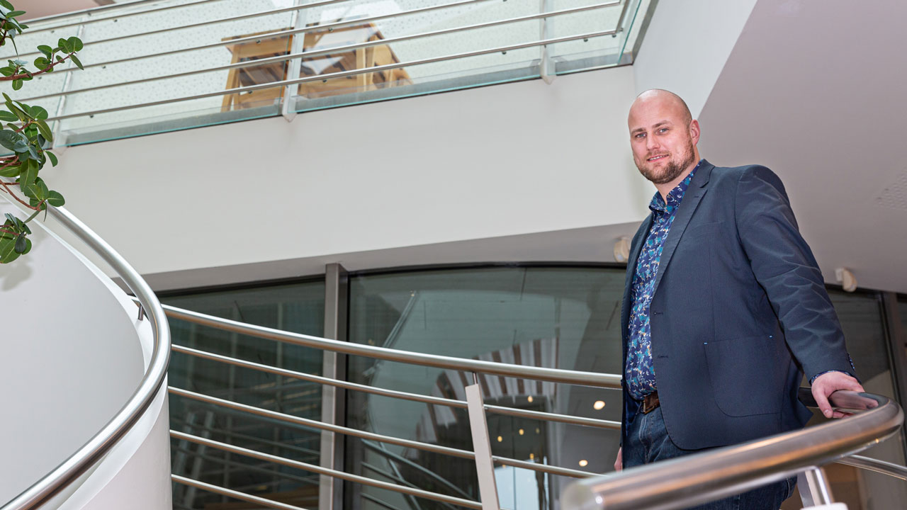 Persoon op moderne trap in duurzaam kantoorgebouw met glas en planten, illustratie van strategisch vastgoedbeheer