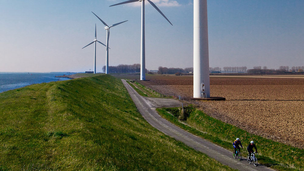 Fietsers op landelijk pad langs windmolens – symbool voor duurzame samenwerking tussen Tetra Tech en provincie Noord-Brabant