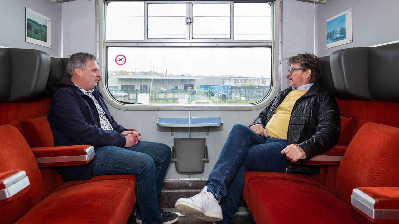 Interieur Hondekop-trein met rode banken, raamzicht en Erik en Herman