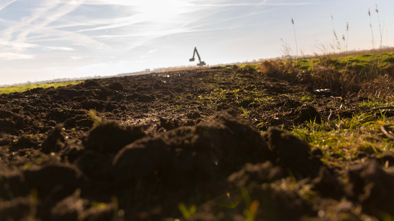 Graafmachine aan het werk aan de horizon tijdens herstelproject in de Oostelijke Vechtplassen