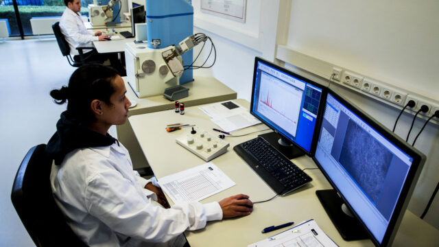 Laboratoriummedewerkers analyseren asbestmonsters met behulp van microscopen en specialistische software